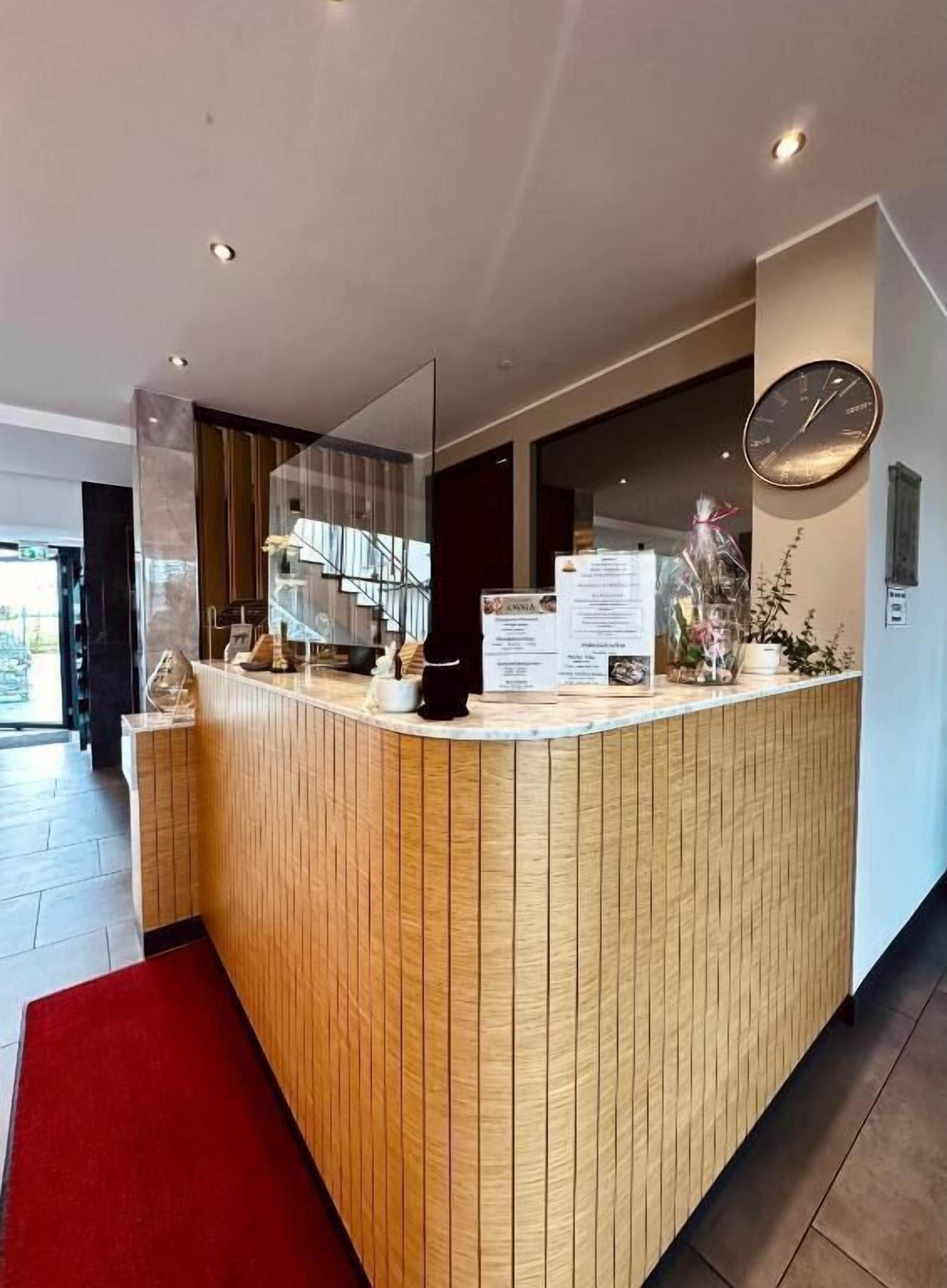 A reception desk with a clock, a menu, and a plant.