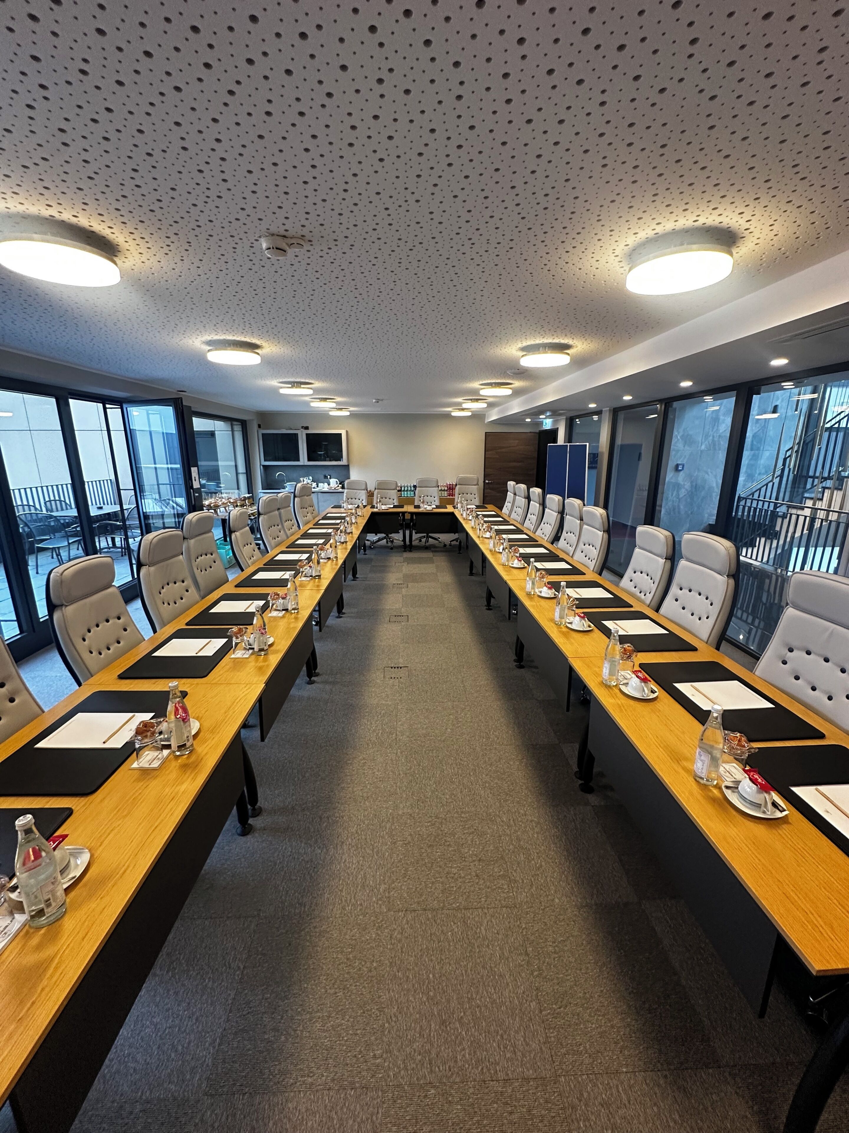 Ein Konferenzraum mit langem Tisch, Stühlen und einer Decke mit Lochpaneelen.