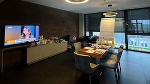 Et moderne spiseområde med fjernsyn, et stort vindue og en tidssvarende lampe.