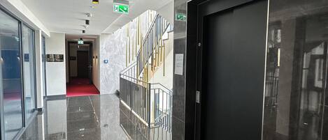 Un pasillo pulido con pisos reflectantes, una escalera y una puerta cerrada.