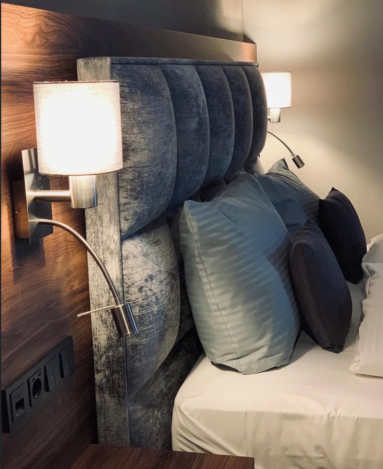 A modern headboard with integrated lighting, a wooden panel, and a neatly arranged bed with pillows.