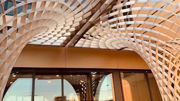 En moderne bygning med en markant, buet glasfacade og en metalramme.
