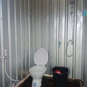 Un baño con inodoro, ducha y un balde.