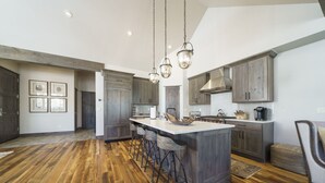 Une cuisine spacieuse dotée d’un îlot central, de planchers en bois et de meubles de cuisine modernes.