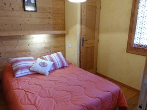 Ein Schlafzimmer mit einem hölzernen Kopfteil, einem Bett mit pinker Bettwäsche und einer Tür mit Fenster.