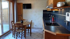 Een keuken met een eettafel, stoelen, een televisie en een radio.