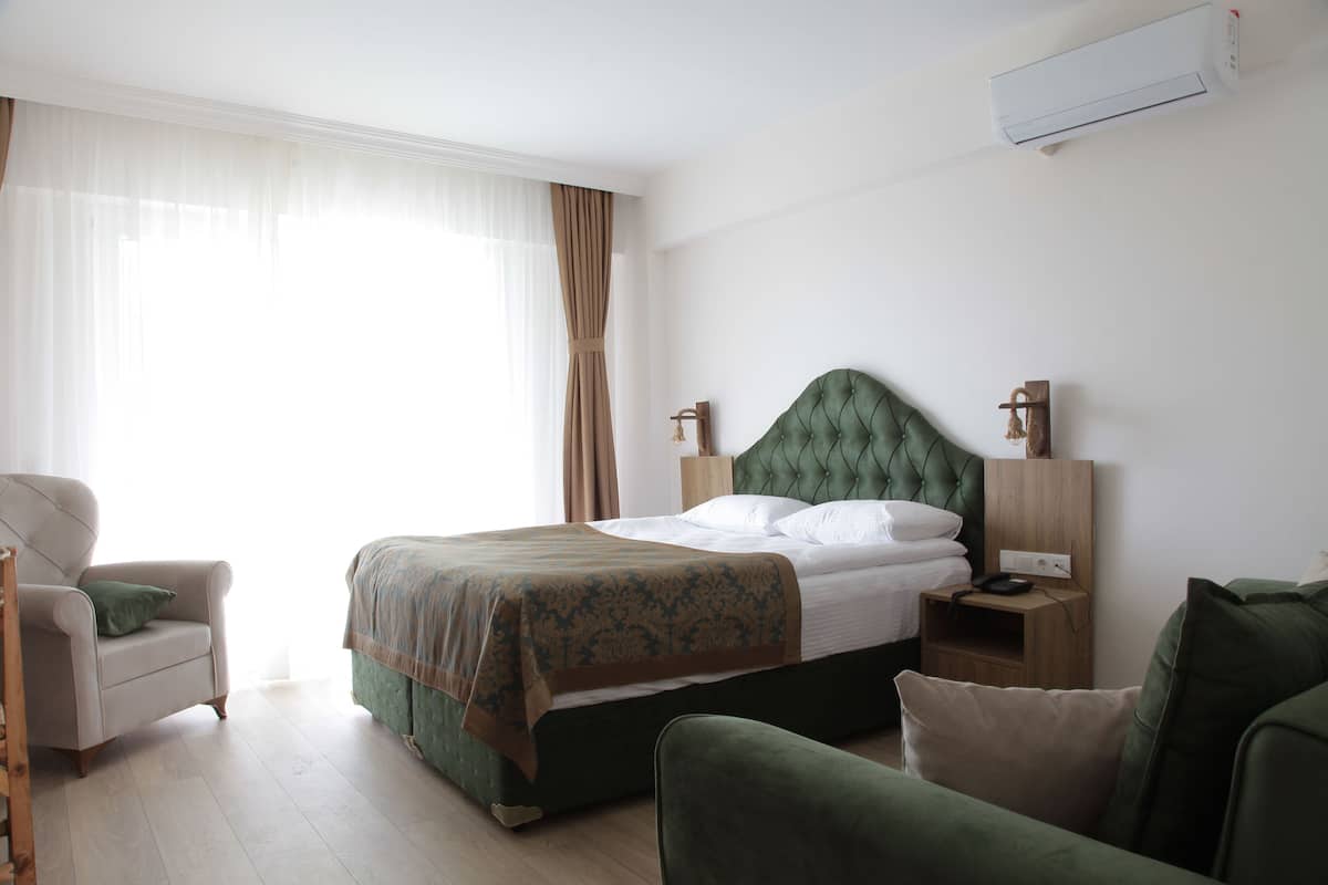 A neatly arranged bedroom with a bed, a chair, a nightstand, and a bedside table.