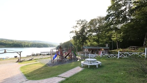 En park med en lekplats, ett picknickbord och utsikt över en sjö.
