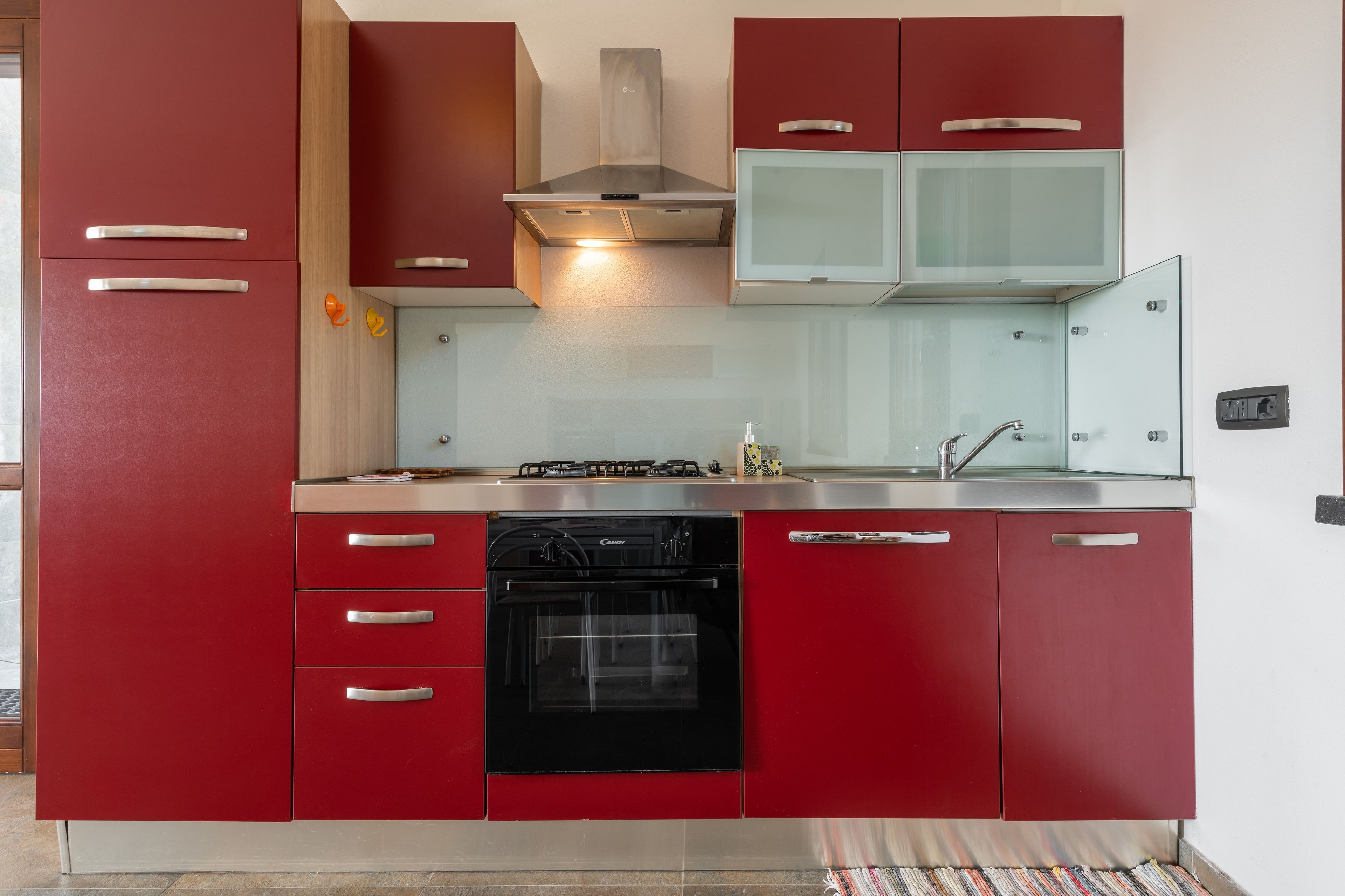 Une cuisine avec des meubles de couleur rouge, un lave-vaisselle noir, une cuisinière en acier inoxydable et un four à micro-ondes.