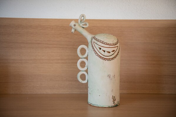 A white ceramic pitcher with a handle and a spout, placed on a wooden surface.