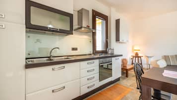 Una cocina moderna con armarios blancos, un lavamanos de acero inoxidable y un horno empotrado.