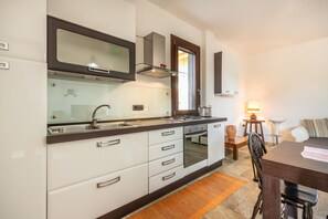 A modern kitchen with white cabinets, a stainless steel sink, and a built-in oven.