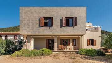 A two-story building with a flat roof, a balcony, and a covered outdoor seating area.