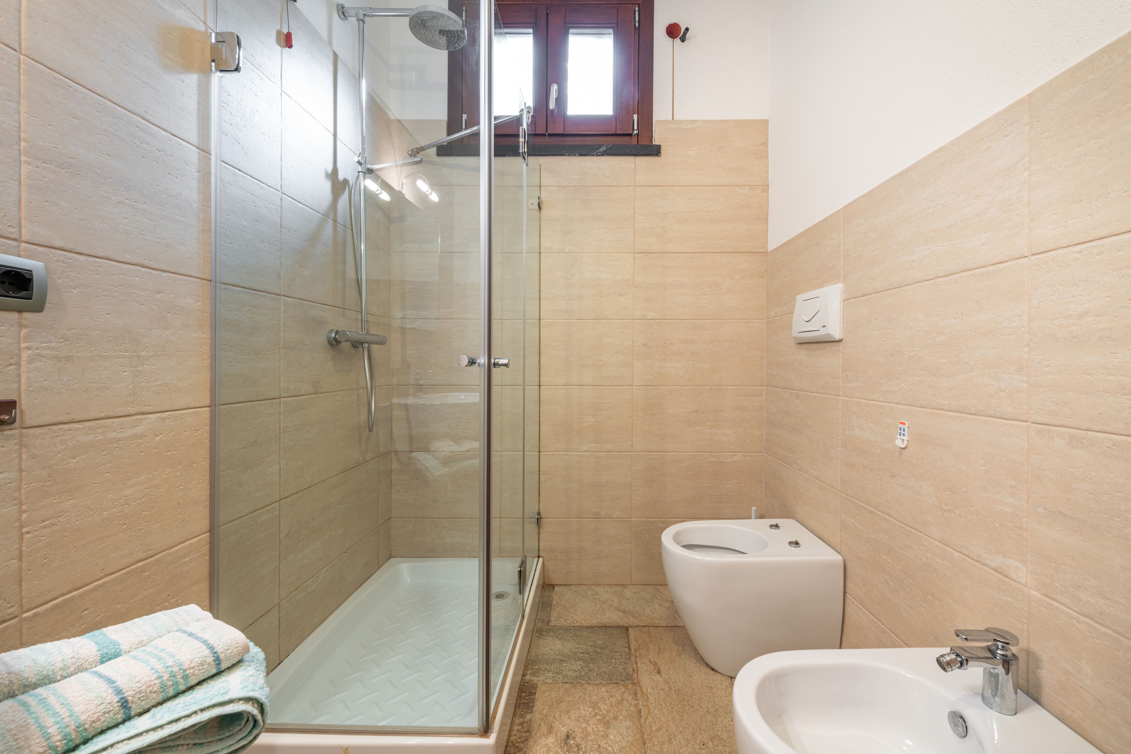 A bathroom with a glass-enclosed shower, a toilet, and a sink.
