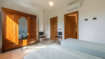 A bedroom with a bed, a wardrobe, a chair, and an air conditioning unit.
