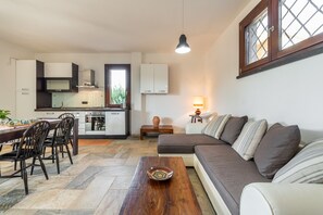 Een moderne woonruimte met een keuken, eethoek en een bank.