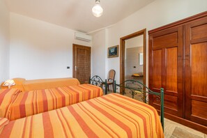 Ein Hotelzimmer mit zwei Betten, einem Holzschrank, einem Spiegel und einer Wand-Klimaanlage.