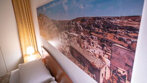 A hotel room with a large cityscape mural on the wall, a bed with white linens, and a lamp on the nightstand. - CasaBattista10 Comfort and Relax (Matera)