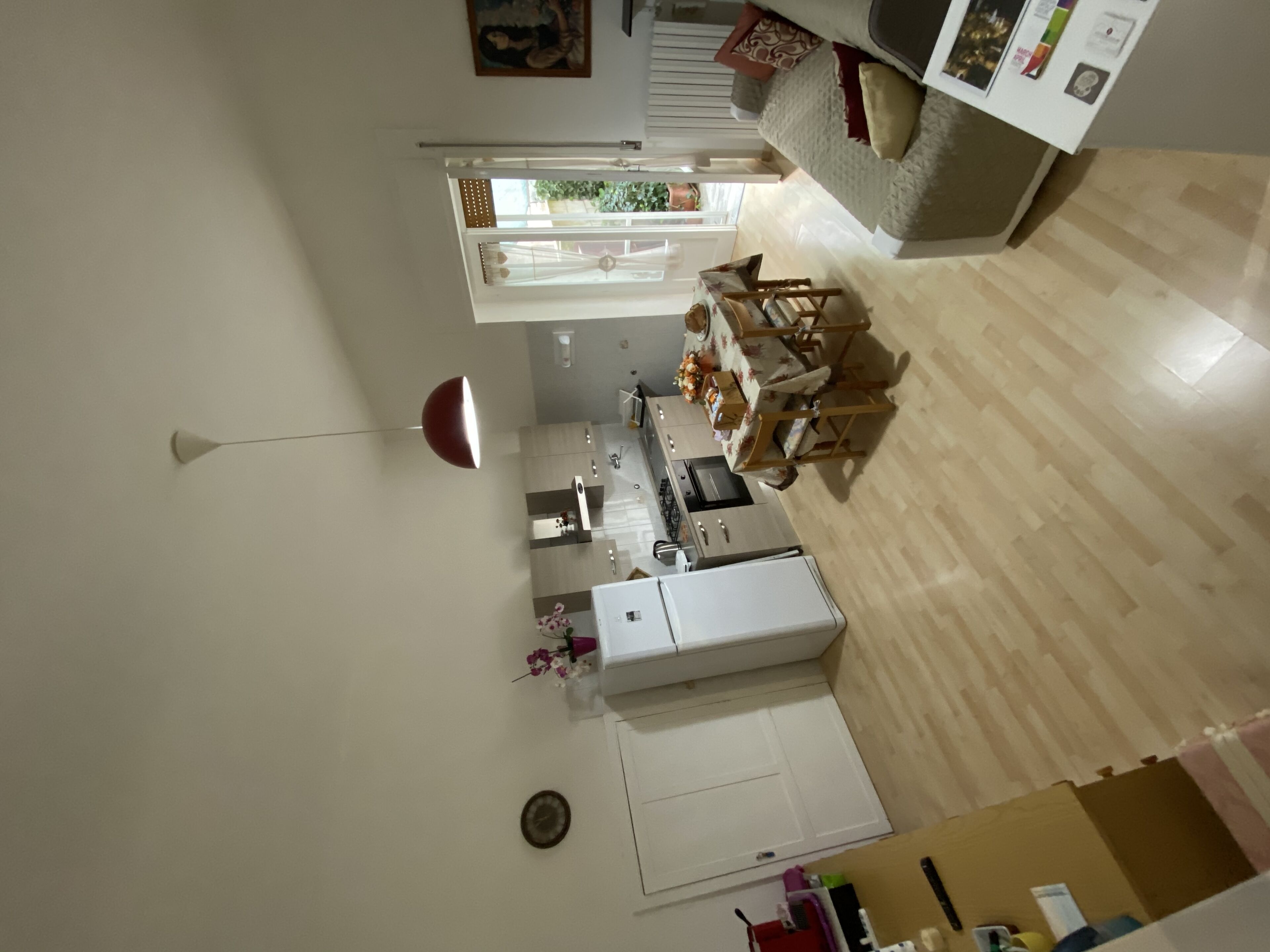 A modern kitchen with wooden ceiling, white cabinets, and a red pendant light.