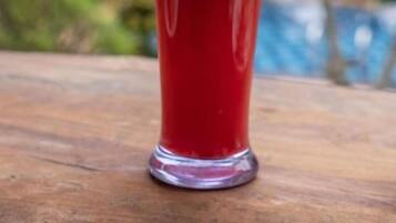 Un verre contenant une boisson rouge, avec une paille et une tranche de fruit, posé sur une surface en bois.