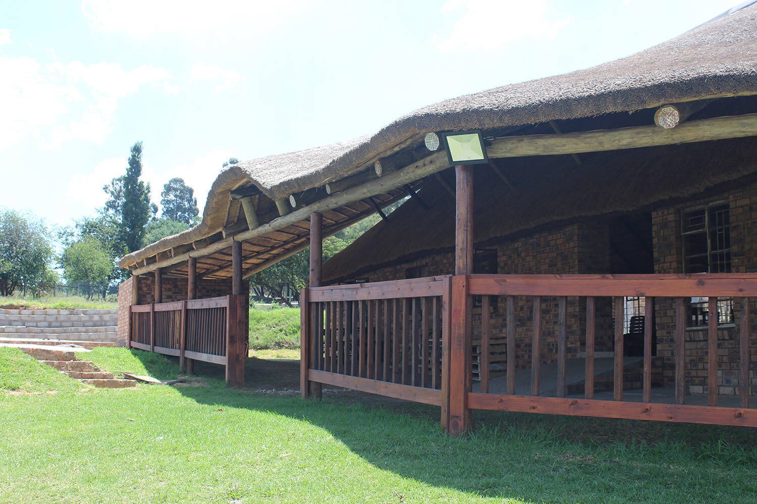 A traditional thatched-roof building with wooden railings and a brick wall.
