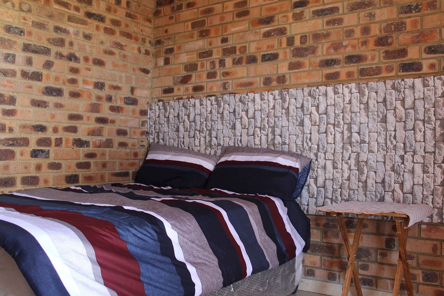Um quarto com parede de tijolos e cabeceira de pedra.