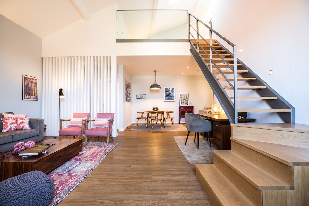 Un salon moderne comprenant un canapé, des fauteuils, une table basse et un escalier menant à un niveau supérieur.