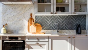 Een keuken met witte kastjes, een backsplash van visgraatmozaïek en een Bosch oven.