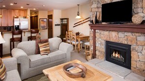 Una sala de estar acogedora con chimenea de piedra, un televisor y un comedor con mobiliario de madera.