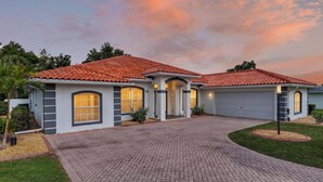 A two-story house with a red-tiled roof, a brick driveway, and a well-maintained lawn. - Stunning Executive Ruyper 4 Bedroom Home by RedAwning (Inverness)