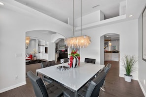 A modern dining area with a large rectangular table, black upholstered chairs, and a decorative centerpiece. - Stunning Executive Ruyper 4 Bedroom Home by RedAwning (Inverness)