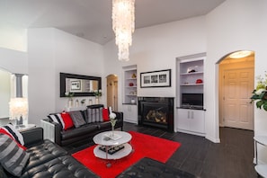 A modern living room with a black leather sofa, a red rug, and a fireplace. - Stunning Executive Ruyper 4 Bedroom Home by RedAwning (Inverness)