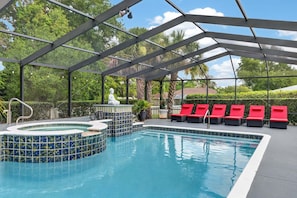 A pool area with a hot tub, red lounge chairs, and a statue. - Stunning Executive Ruyper 4 Bedroom Home by RedAwning (Inverness)