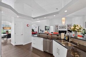 A modern kitchen with white cabinetry, a stainless steel dishwasher, and a black countertop.