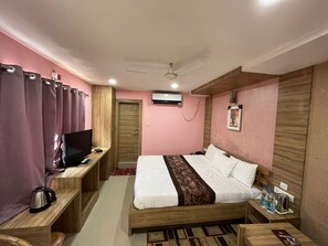 A hotel room with a bed, a desk, a television, a wardrobe, and a ceiling fan. - Hotel Pratap Residency (Ranchi)