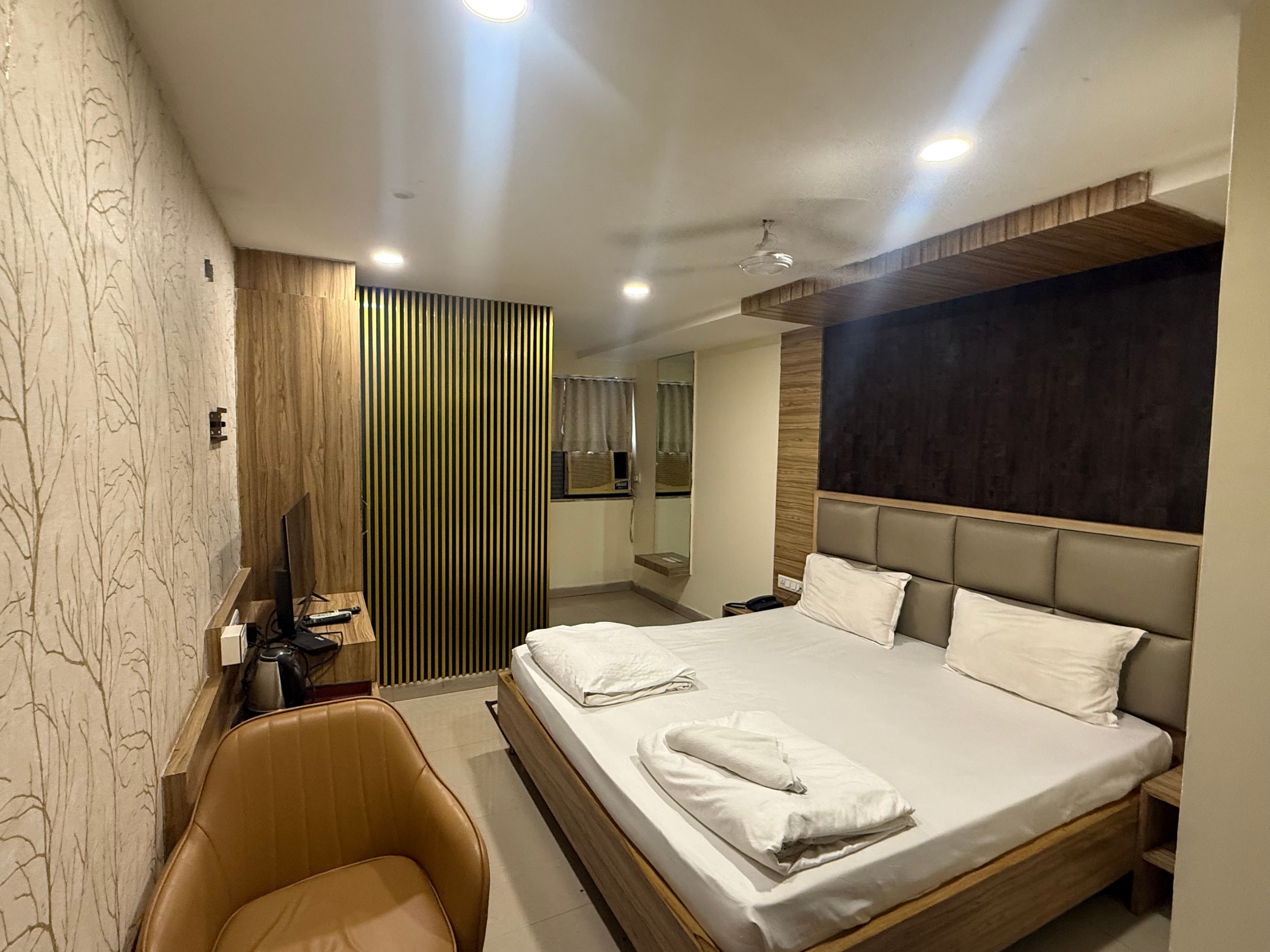 Habitació d'hotel moderna amb un llit gran, un escriptori, una cadira i un mirall.