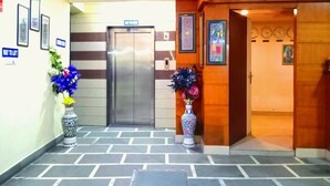 Un vestíbulo de hotel con una recepción, un ascensor y una puerta de madera.