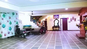 Un hall con suelo de baldosas, una escalera, un mostrador de recepción y una pared decorada con cuadros.