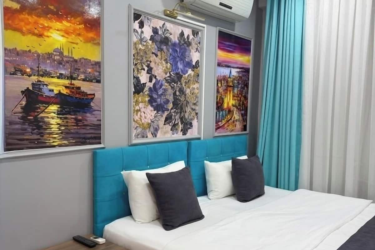 A modern bedroom with a bed, a nightstand, and a wall-mounted air conditioner.
