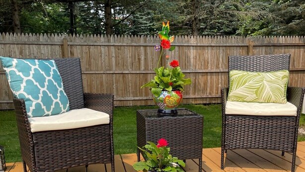 A wooden deck with three wicker chairs, each with a cushion. There are potted plants with flowers on the deck. - Nestled in the Beekman Art District (Saratoga Springs)