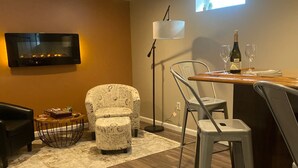 A modern living room with a fireplace, a flat-screen TV, and a dining area with a table and chairs. - Nestled in the Beekman Art District (Saratoga Springs)