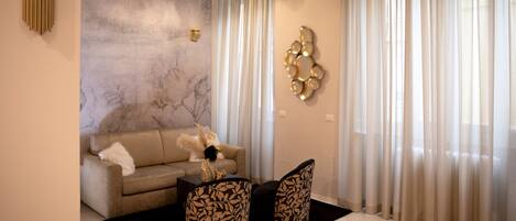 A modern living room with a sofa, two chairs, a decorative wall piece, and a ceiling light.