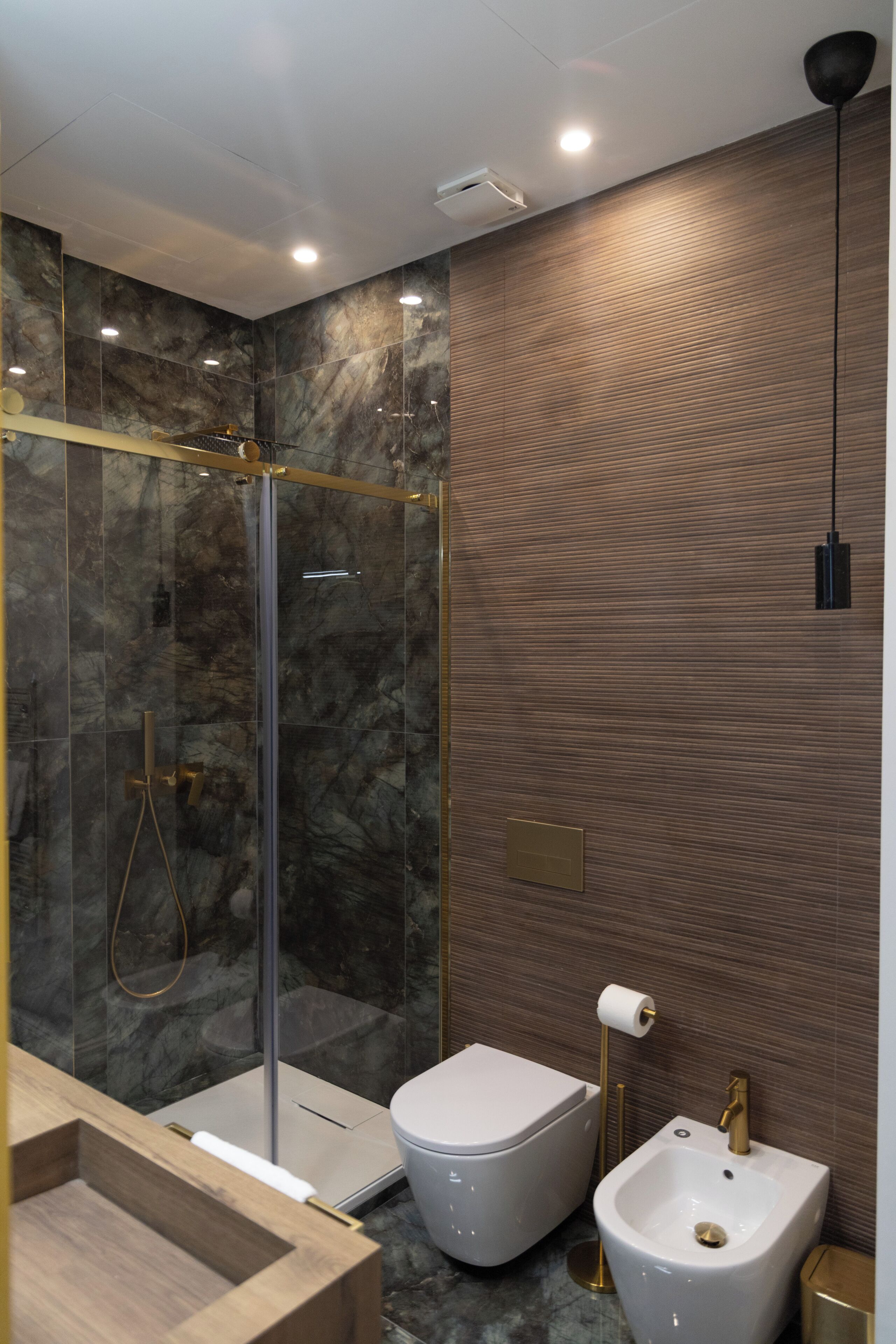 Un bagno moderno con doccia vetro, water e bidet.