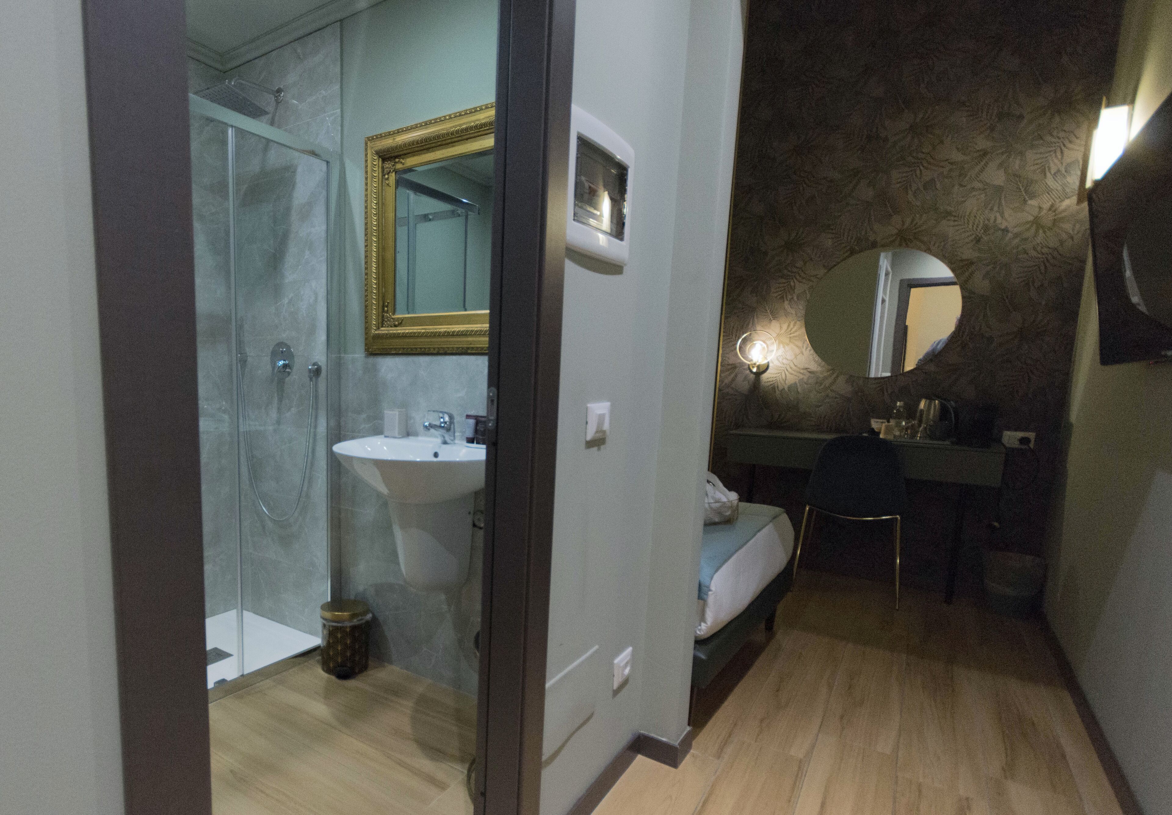 Habitación de hotel con ducha, lavabo y cama.