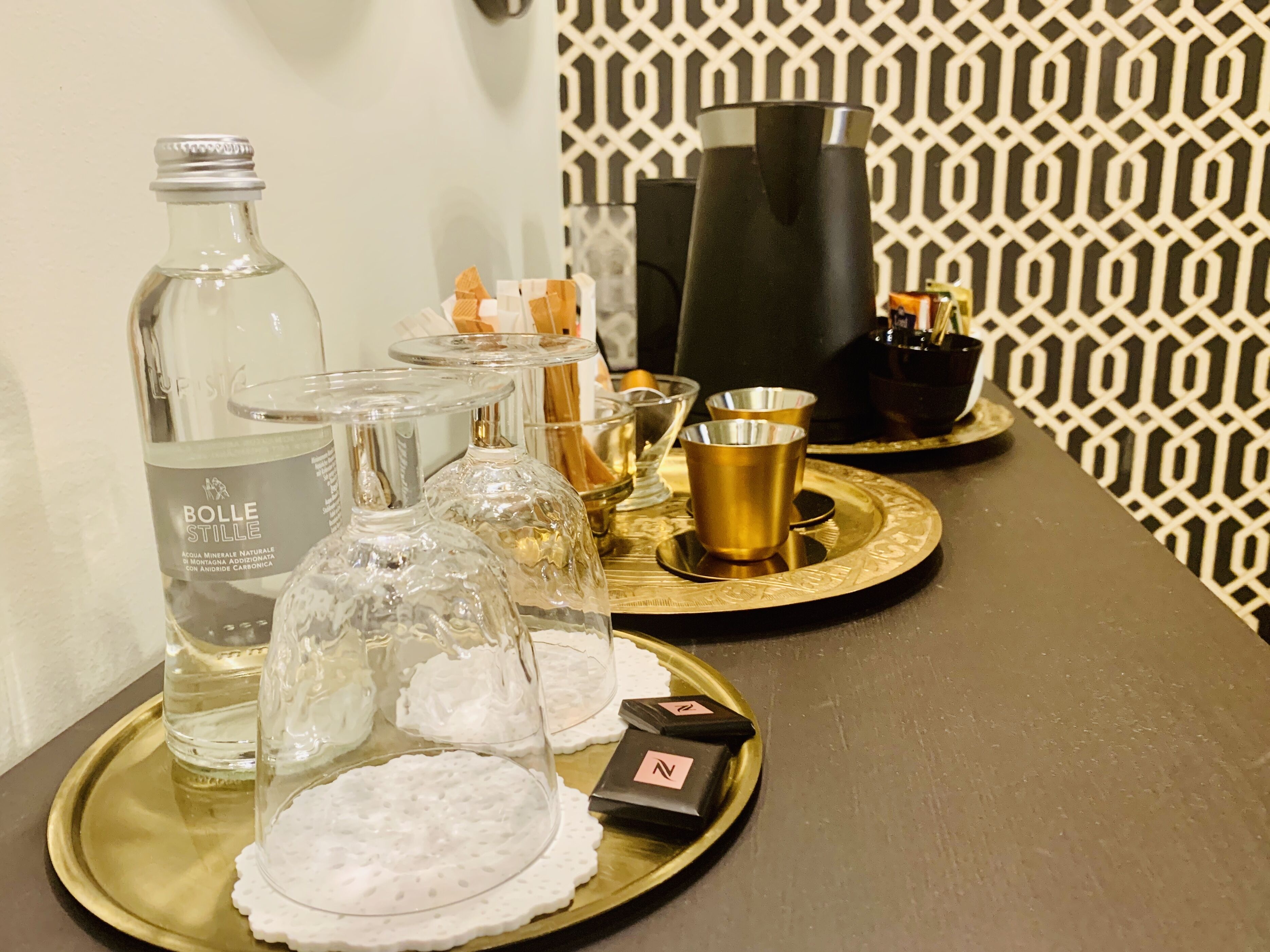 A table with a bottle of water, glasses, and a tray with small containers.