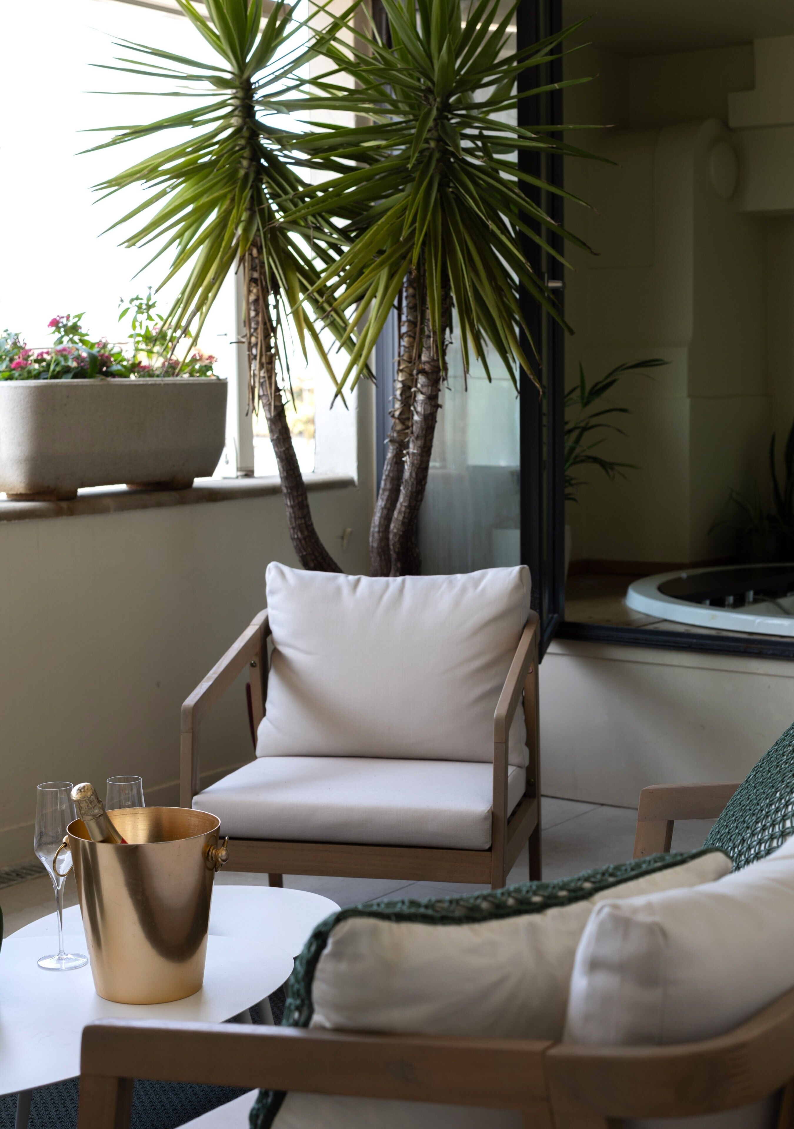 A room with a chair, a table, a potted plant, and a window.