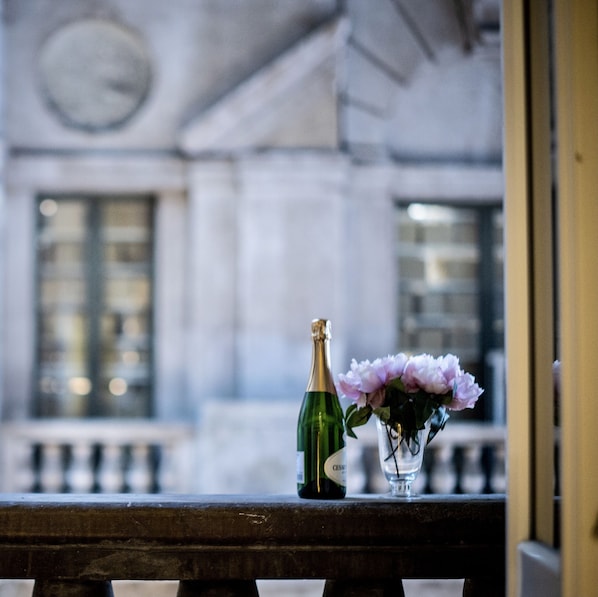Una botella de champán y un florero con flores en el alféizar de una ventana.