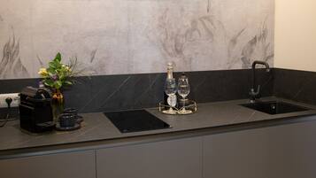 A modern kitchen with a marble backsplash, a built-in sink, and a countertop with a coffee machine and a vase with flowers.