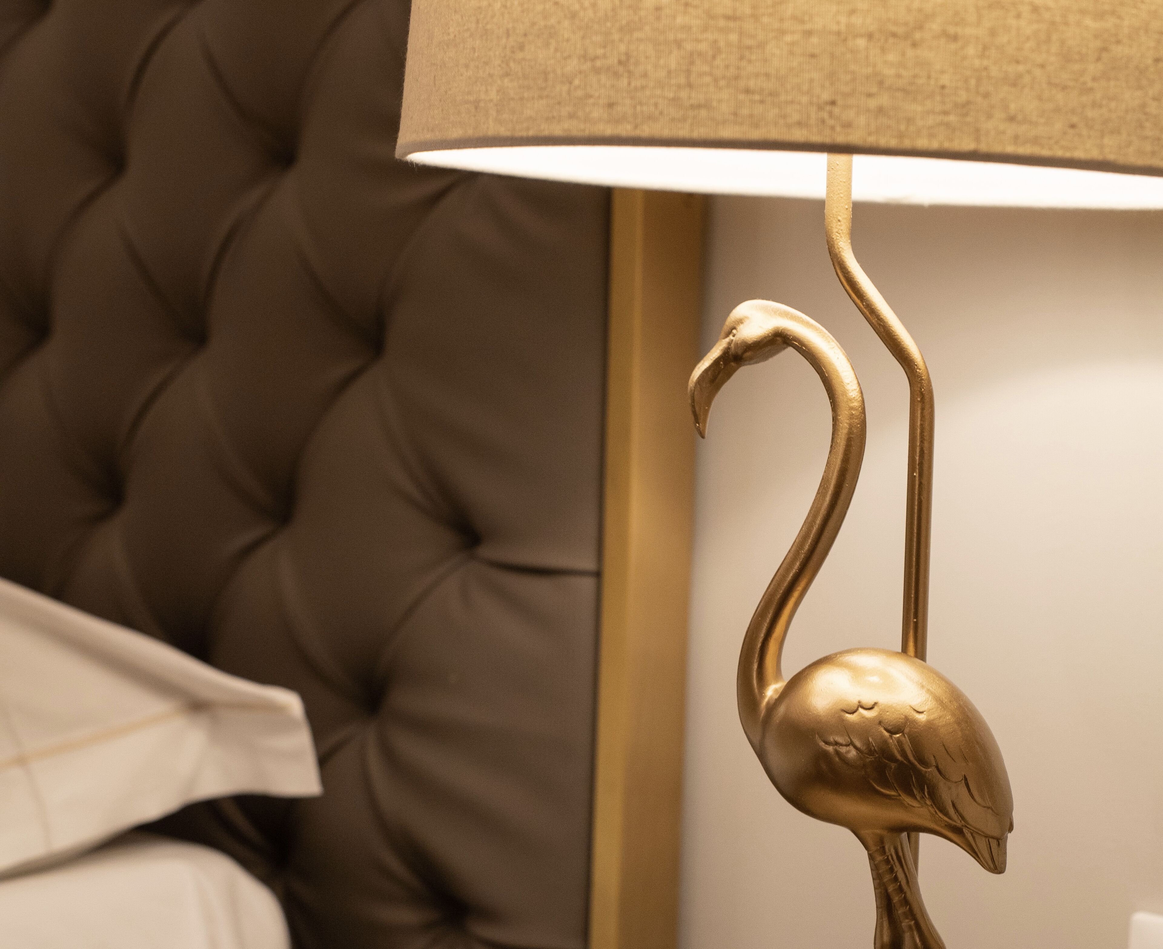 Ein gebürstetes Kopfbrett und eine goldfarbene, schwanförmige Lampe.