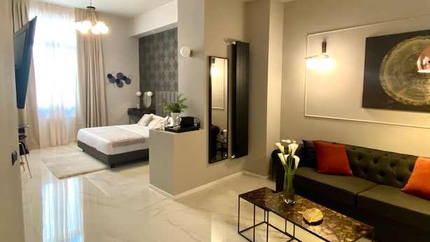A modern hotel room with a bed, a sofa, a coffee table, and a large mirror. - INTOMILAN  Galleria Duomo - Boutique & Design Aparthotel (Milan)